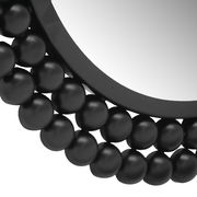 Nahaufnahme eines runden Spiegels mit einem dekorativen schwarzen Rahmen aus kugelförmigen Elementen, perspektivisch von der Seite aufgenommen.
