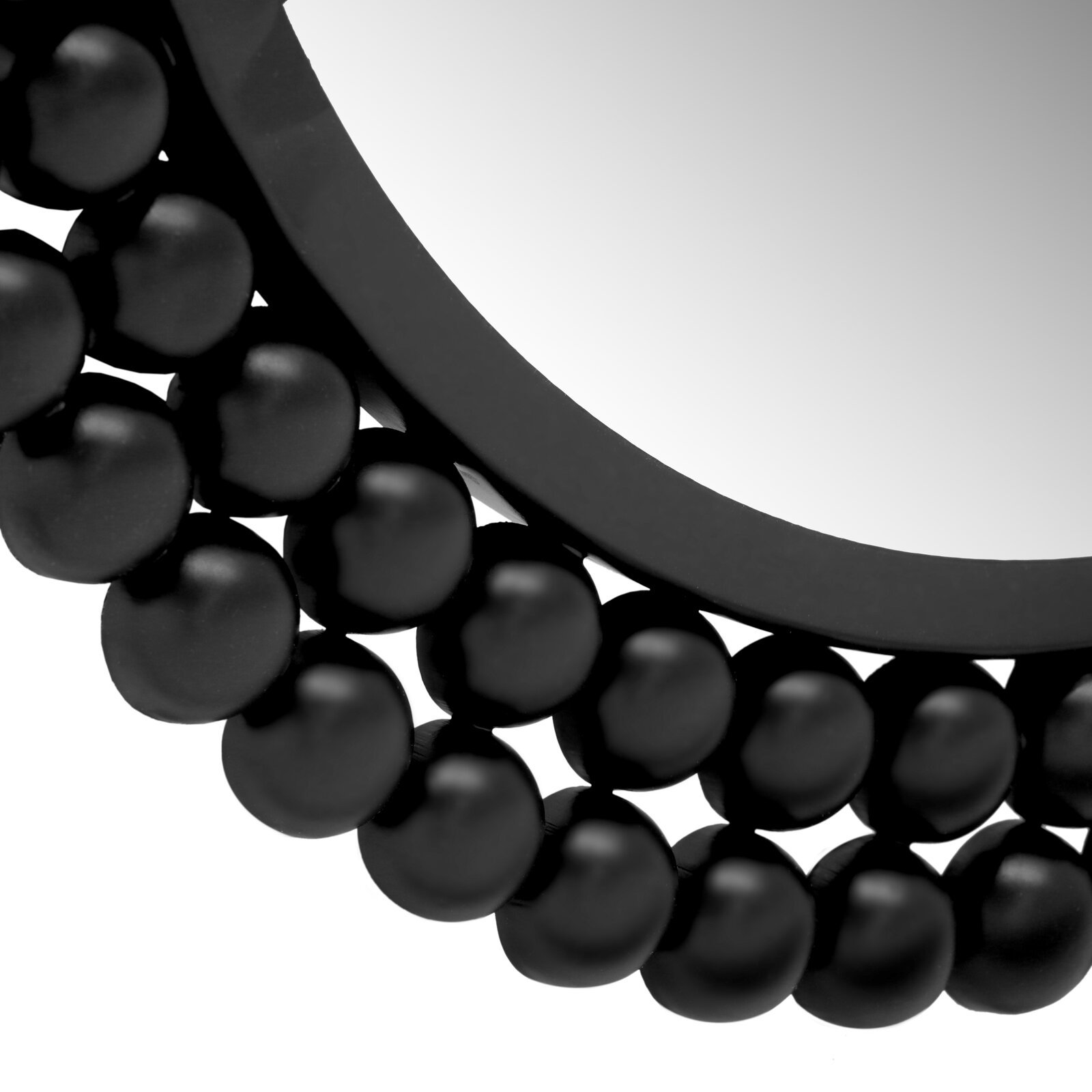 Nahaufnahme eines runden Spiegels mit einem dekorativen schwarzen Rahmen aus kugelförmigen Elementen, perspektivisch von der Seite aufgenommen.