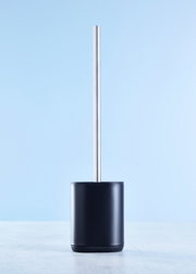 Toilettenbürste in modernem Design, frontal fotografiert, mit schwarzem Behälter und silbernem Stiel vor blauem Hintergrund.