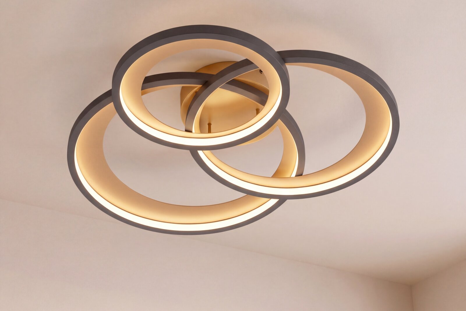 Moderne LED-Deckenleuchte mit drei überlappenden, runden Lichtringen in warmweiß, Ansicht von unten in leichter Schrägperspektive an der Decke montiert.