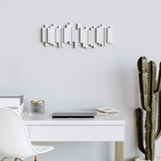 Moderne Wandgarderobe in geometrischem Design, frontal an einer hellen Wand über einem Schreibtisch mit Dekorationen und einem Kaktus platziert.