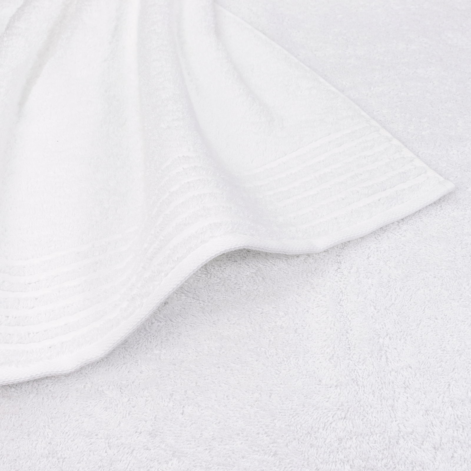 Nahaufnahme eines weißen Handtuchs mit feinen Streifen am Rand, flach auf einer Oberfläche liegend.