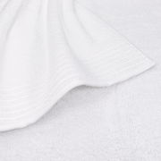 Nahaufnahme eines weißen Handtuchs mit feinen Streifen am Rand, flach auf einer Oberfläche liegend.