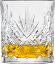 Nahaufnahme eines Whiskyglases mit aufwendigem Schliffmuster und goldenem Getränk, seitliche Perspektive.