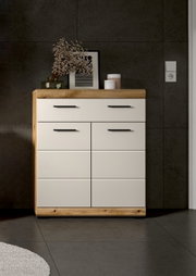 Moderne Kommode in Weiß mit Holzrahmen und schwarzen Griffen, frontal aus Augenhöhe vor dunkler Wand, dekoriert mit Vase, Bild und Dosen auf der Ablage.