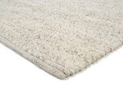 Nahaufnahme eines handgewebten Teppichs in hellen Naturtönen, seitliche Perspektive