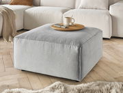 Grauer Hocker aus Cordstoff in einer gemütlichen Wohnzimmerumgebung, seitliche Perspektive.