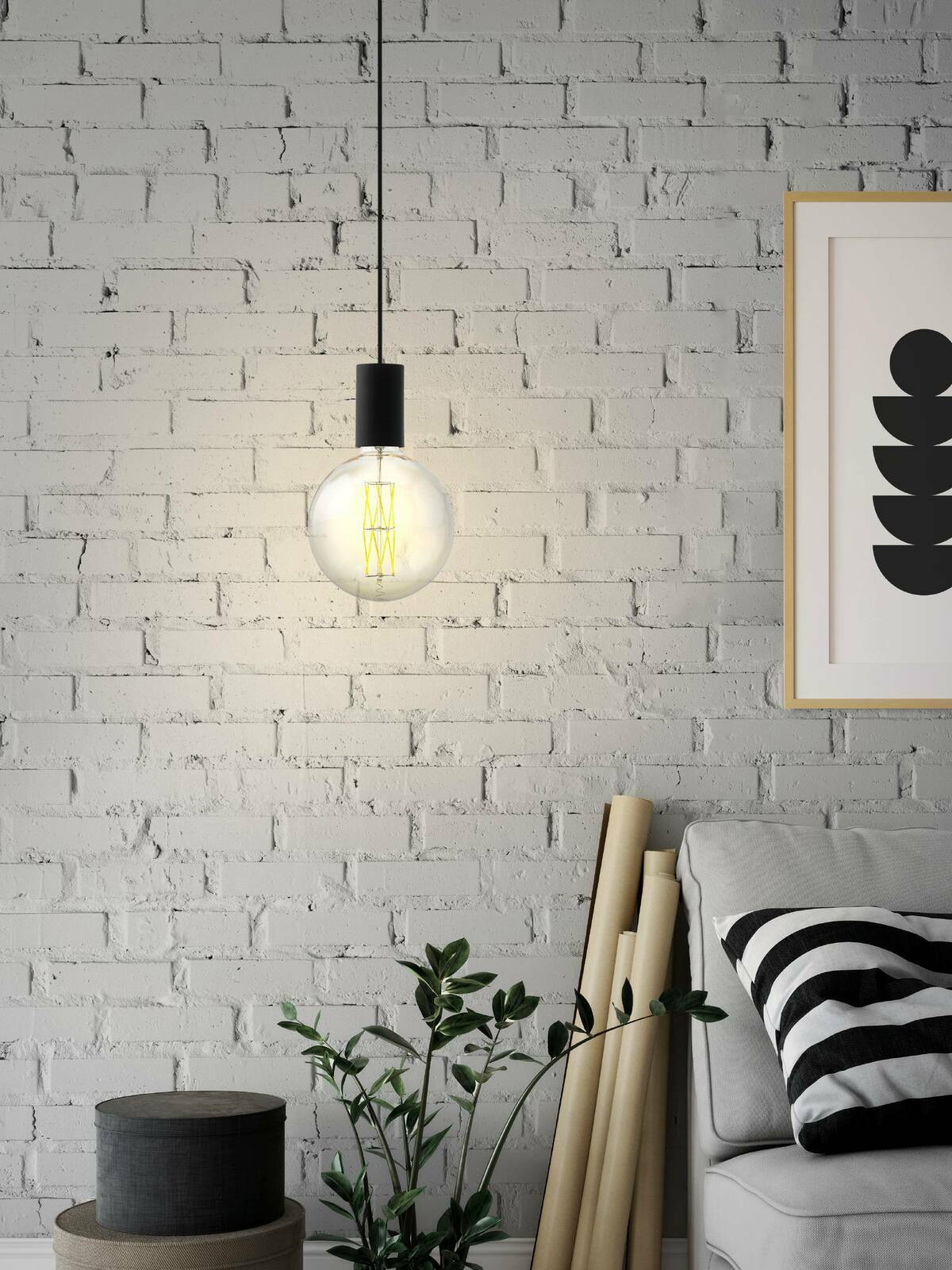 Moderne Pendelleuchte POZUETA mit schwarzem Kabel und runder Glühbirne, vor einer weißen Ziegelwand hängend. Perspektive von vorne.