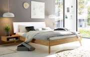 Modernes Schlafzimmer mit gepolstertem Kopfteil in einem hellen Raum mit großen Fenstern, seitliche Perspektive.