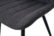 Detailaufnahme der gepolsterten Sitzfläche eines Stuhls mit dunkelgrauem Stoffbezug und schwarzen Metallbeinen, Perspektive schräg von oben