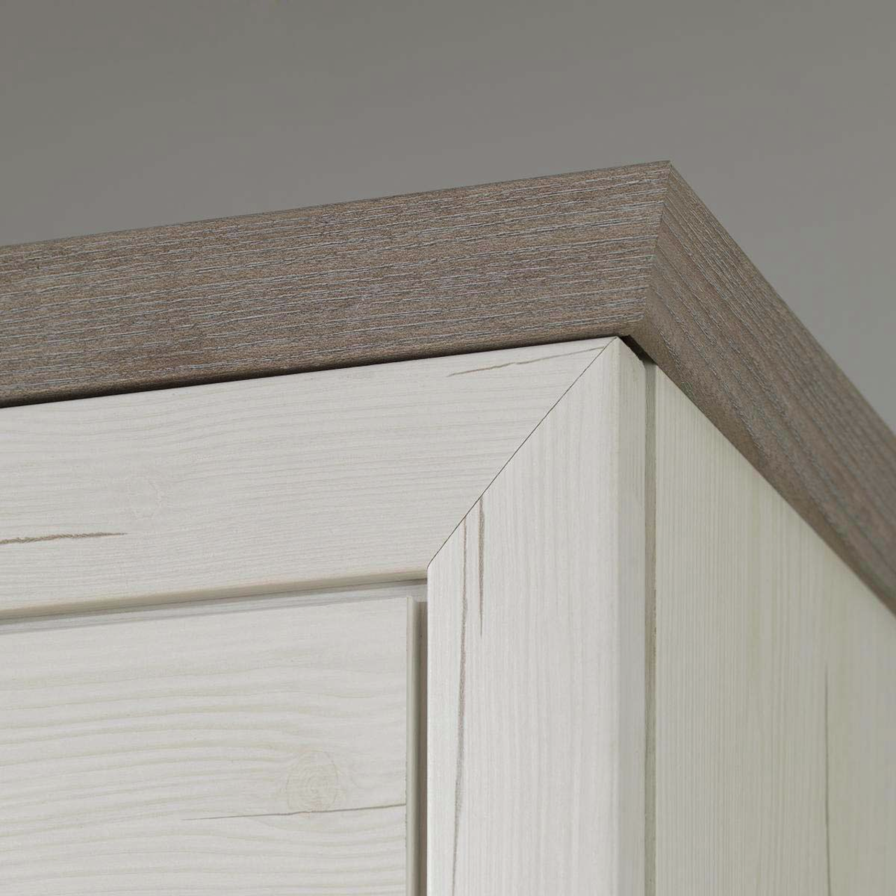 Nahaufnahme der oberen Ecke eines Sideboards aus hellem Holz mit dunklerer Holzplatte, Perspektive von unten.