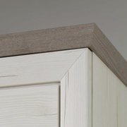 Nahaufnahme der oberen Ecke eines Sideboards aus hellem Holz mit dunklerer Holzplatte, Perspektive von unten.