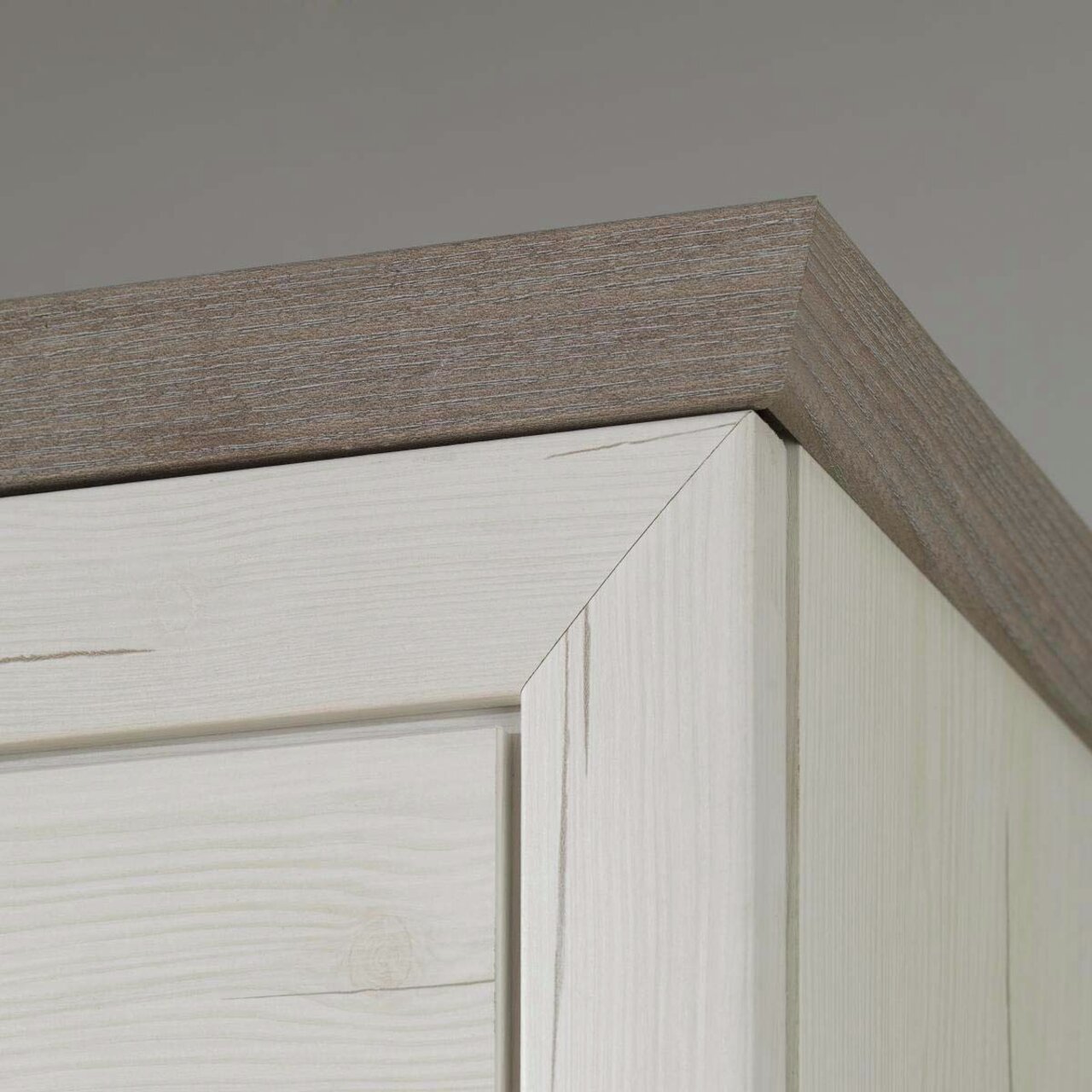 Nahaufnahme der oberen Ecke eines Sideboards aus hellem Holz mit dunklerer Holzplatte, Perspektive von unten.