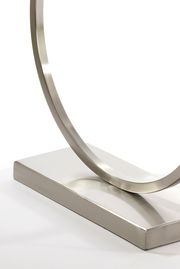 Nahaufnahme eines modernen, gebürsteten Metall-Lampenfußes mit kreisförmigem Design auf rechteckiger Basis, seitliche Perspektive.