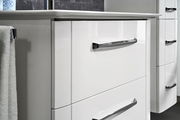 Nahaufnahme eines weißen Waschtischunterschranks mit glänzenden Chromgriffen, seitliche Perspektive