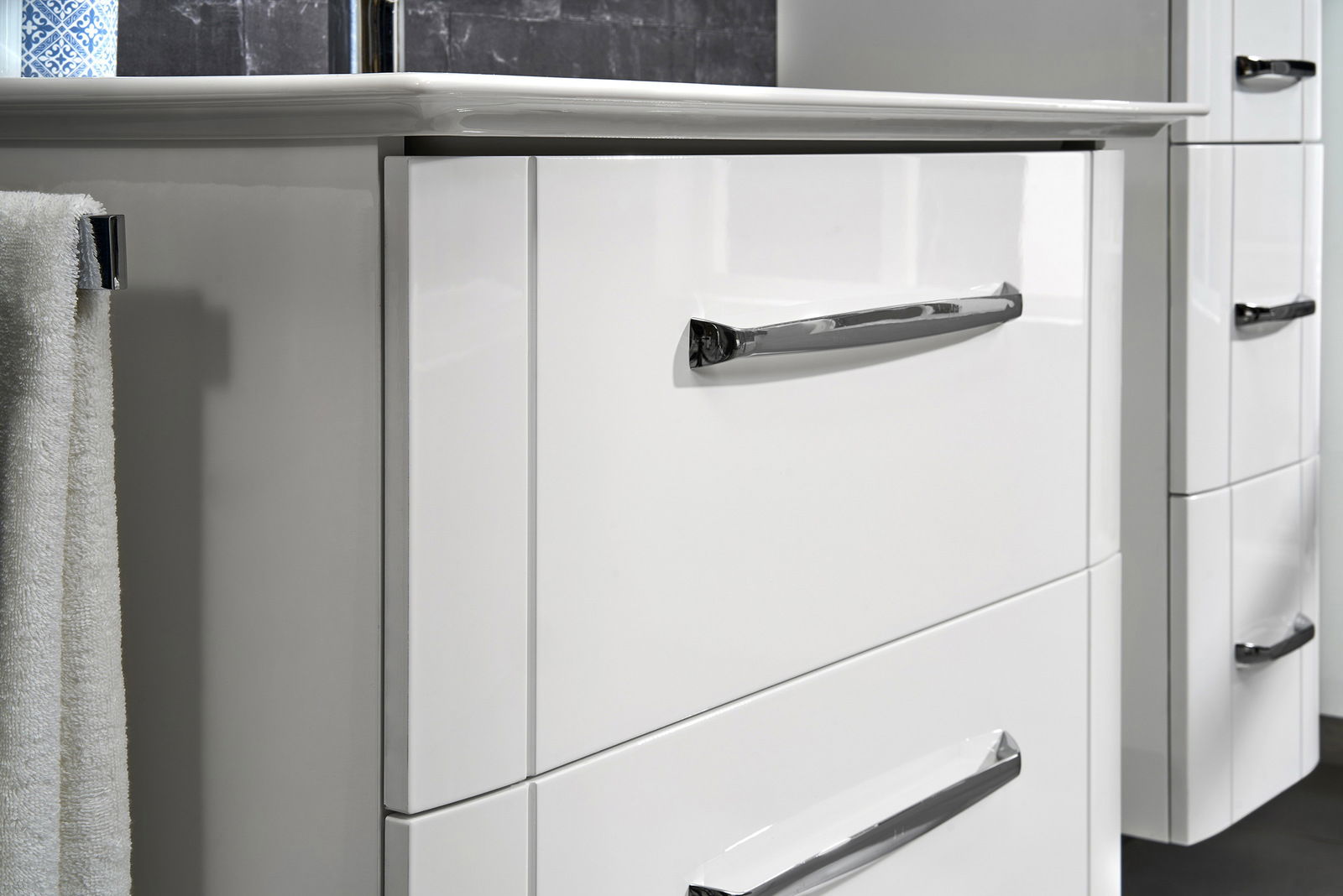 Nahaufnahme eines weißen Waschtischunterschranks mit glänzenden Chromgriffen, seitliche Perspektive