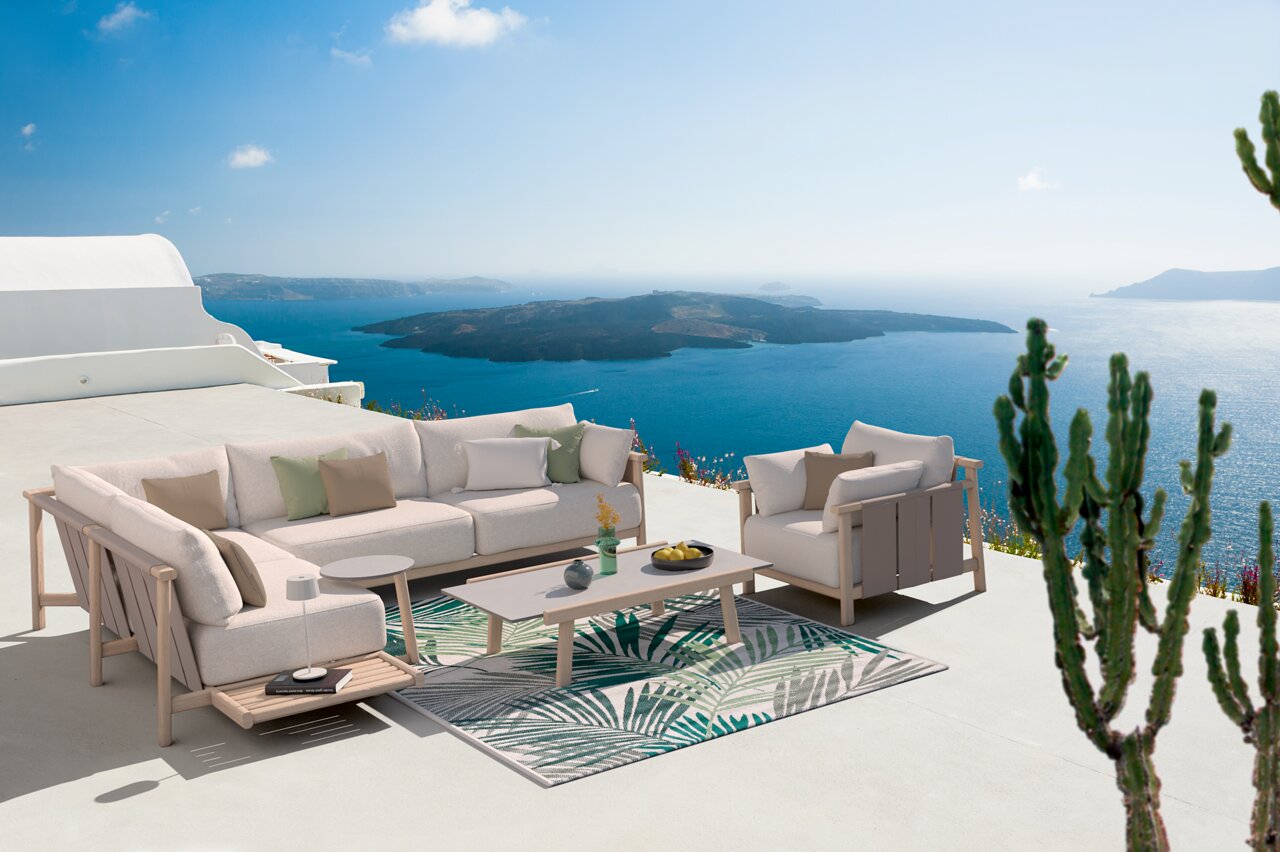 Moderne Loungeecke mit Sofa und Tisch auf einer Terrasse mit Meerblick, seitliche Perspektive