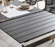 Moderner Ausziehtisch mit dunkler Tischplatte und Metallrahmen, gedeckt mit Geschirr und Gläsern, seitliche Perspektive.