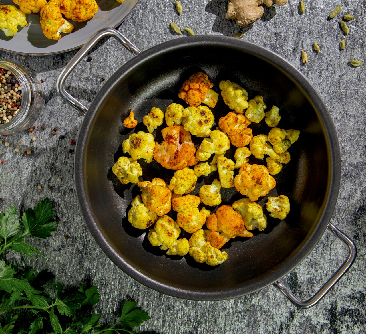 Servierpfanne XL CLASSIC 24 cm mit gebratenem Blumenkohl, von oben fotografiert, umgeben von Gewürzen und Kräutern.