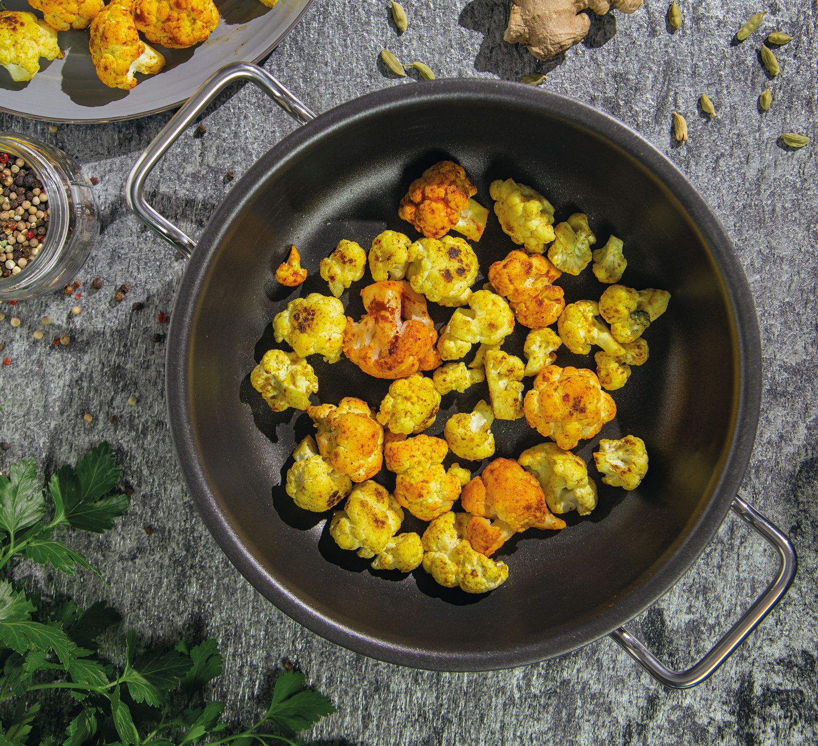 Servierpfanne XL CLASSIC 24 cm mit gebratenem Blumenkohl, von oben fotografiert, umgeben von Gewürzen und Kräutern.