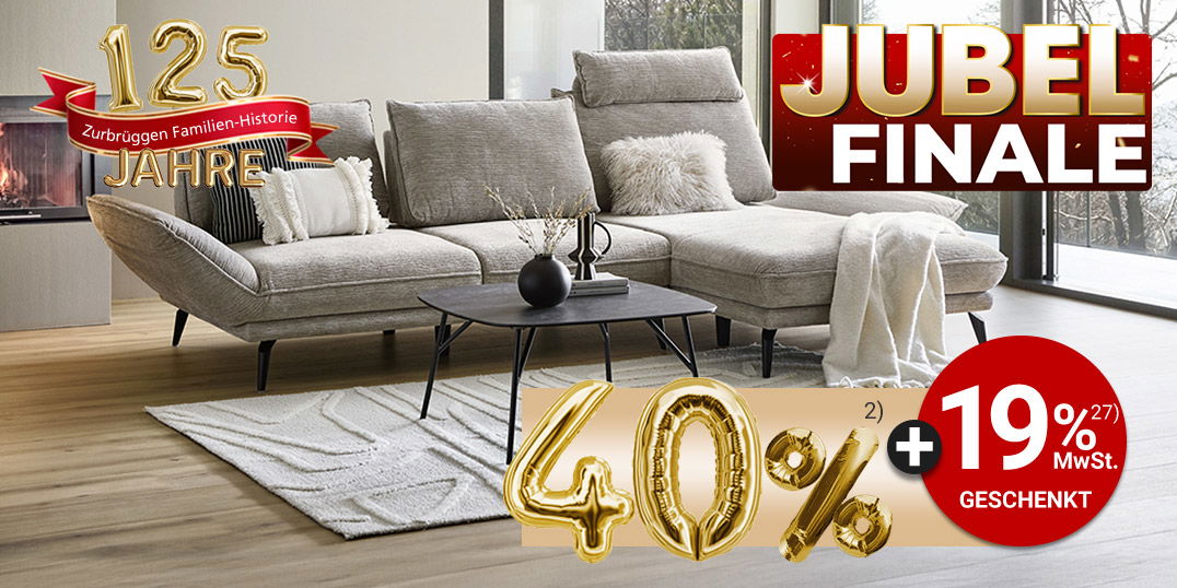 Modernes Wohnzimmer mit hellem Sofa vor Panoramafenstern, Kaminfeuer und Jubiläumsbanner „125 Jahre – Jubel Finale