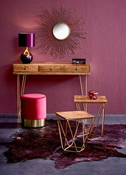 Konsolentisch aus Holz mit goldenen Beinen, dekoriert mit einer violetten Lampe und einem runden Spiegel an der Wand, aus der Frontalperspektive.