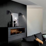 Moderne schwarze Wand-Spotleuchten als Paar über einem Sideboard an dunkler Akzentwand, Innenraumaufnahme in leichter Schrägansicht von vorn links
