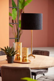 Schwarzer ovaler Lampenschirm auf einem goldenen Ständer, auf einem Tisch mit Dekorationen, seitliche Perspektive