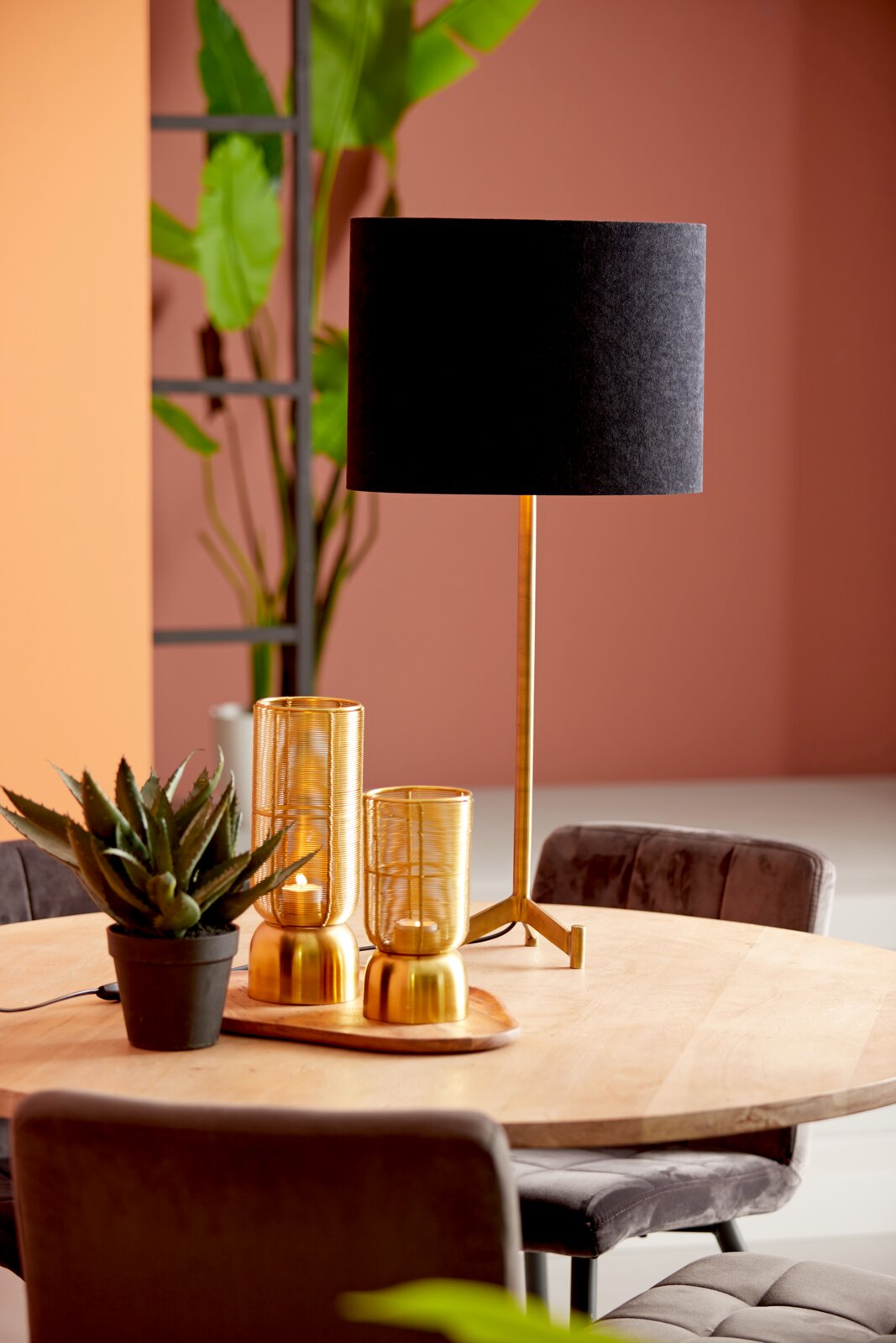 Schwarzer ovaler Lampenschirm auf einem goldenen Ständer, auf einem Tisch mit Dekorationen, seitliche Perspektive