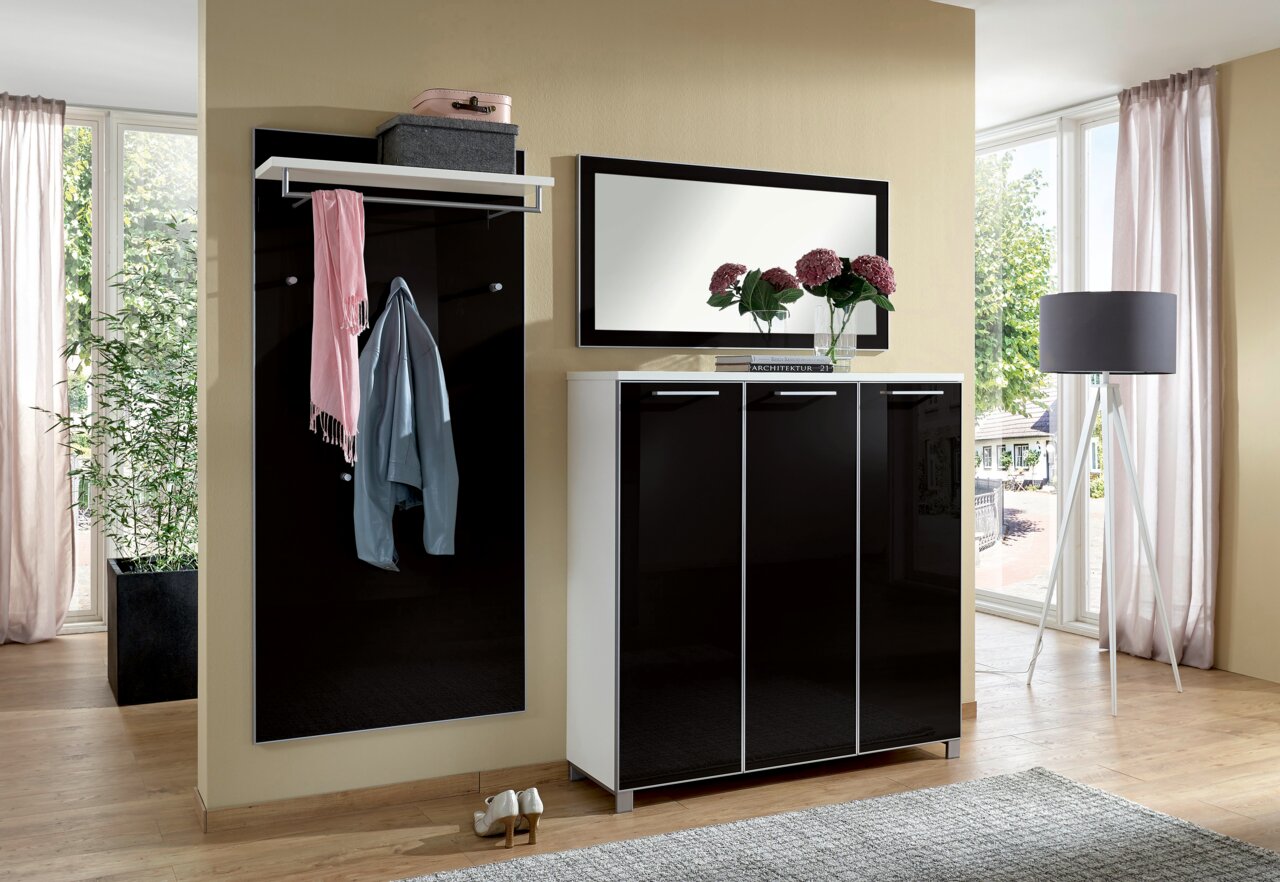 Modernes Garderoben-Set in schwarzem Hochglanz mit Spiegel, Schuhschrank und Kleiderhaken, seitliche Perspektive.