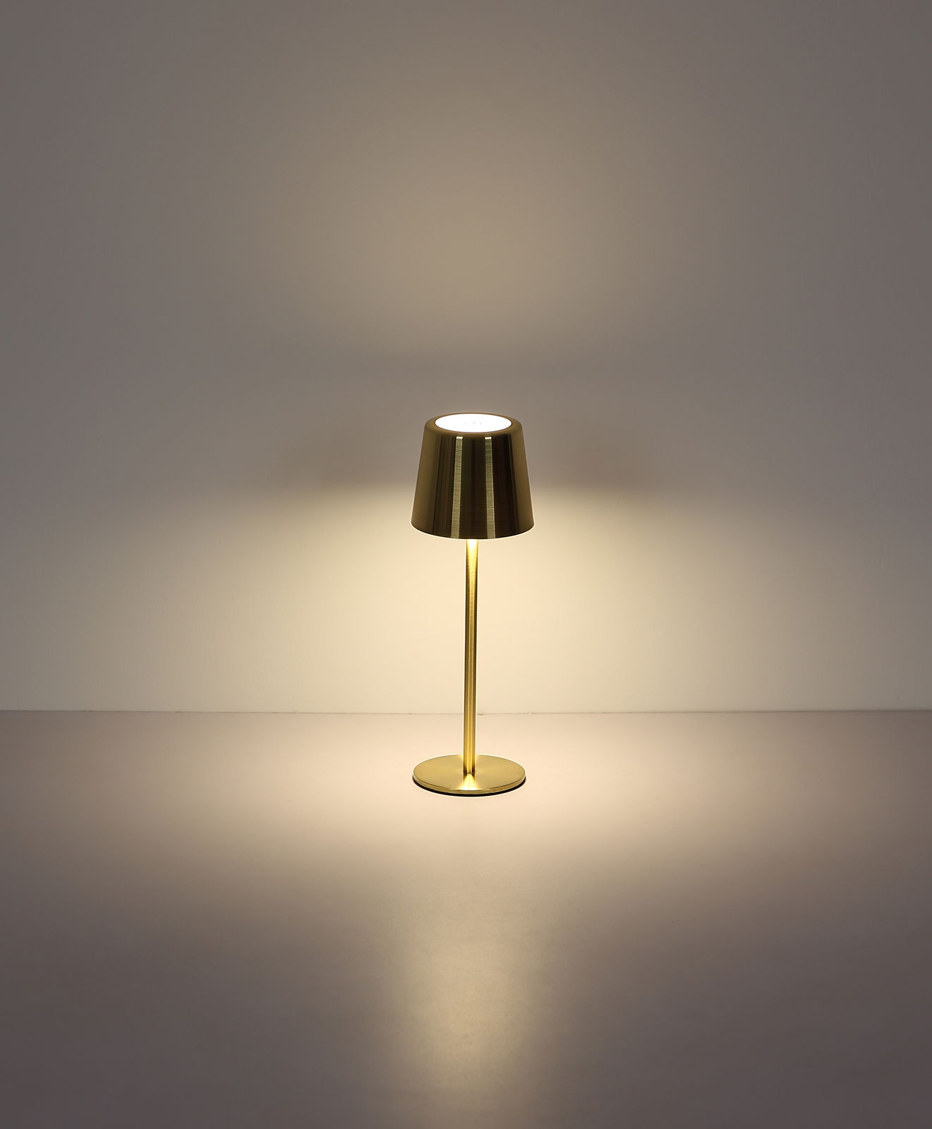 Elegante Tischleuchte aus Metall in Gold, frontal beleuchtet auf neutralem Hintergrund.
