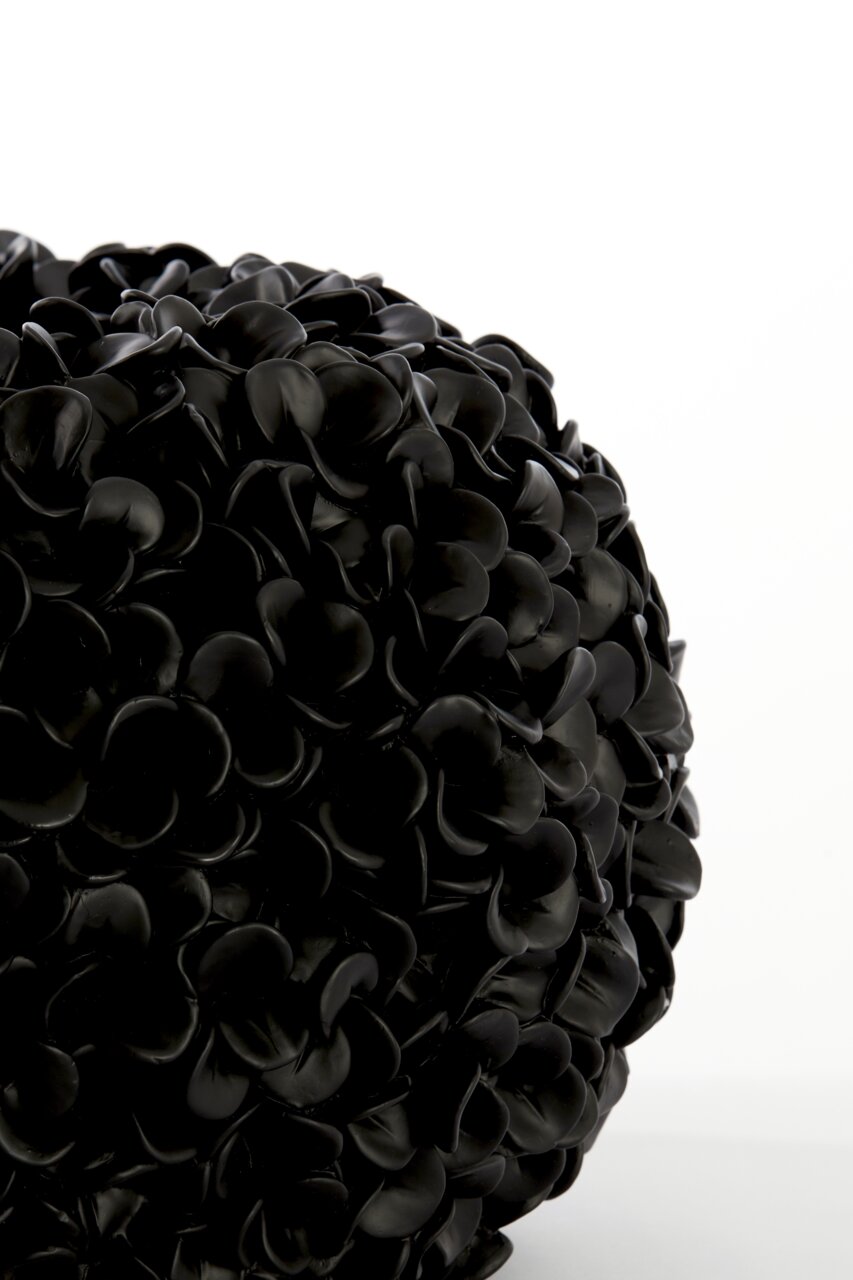 Nahaufnahme einer schwarzen Vase mit mattem Finish und blütenblattartiger Struktur, seitliche Perspektive.