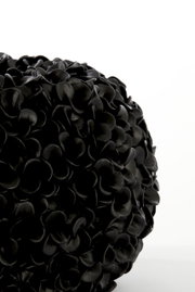 Nahaufnahme einer schwarzen Vase mit mattem Finish und blütenblattartiger Struktur, seitliche Perspektive.