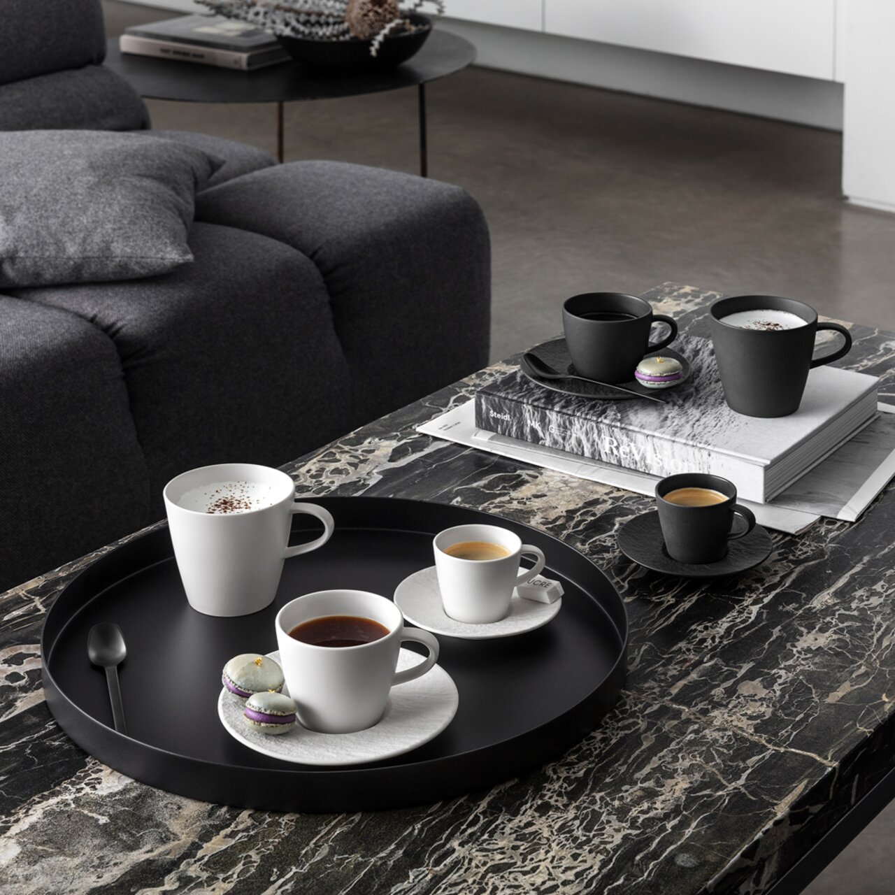Een set espressokopjes op een stijlvolle marmeren tafel, met een zwart-wit ontwerp, gefotografeerd vanuit vogelperspectief.