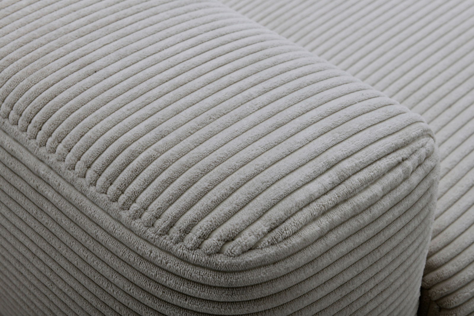 Nahaufnahme eines grauen, gerippten Stoffes eines Funktionssofas aus seitlicher Perspektive.