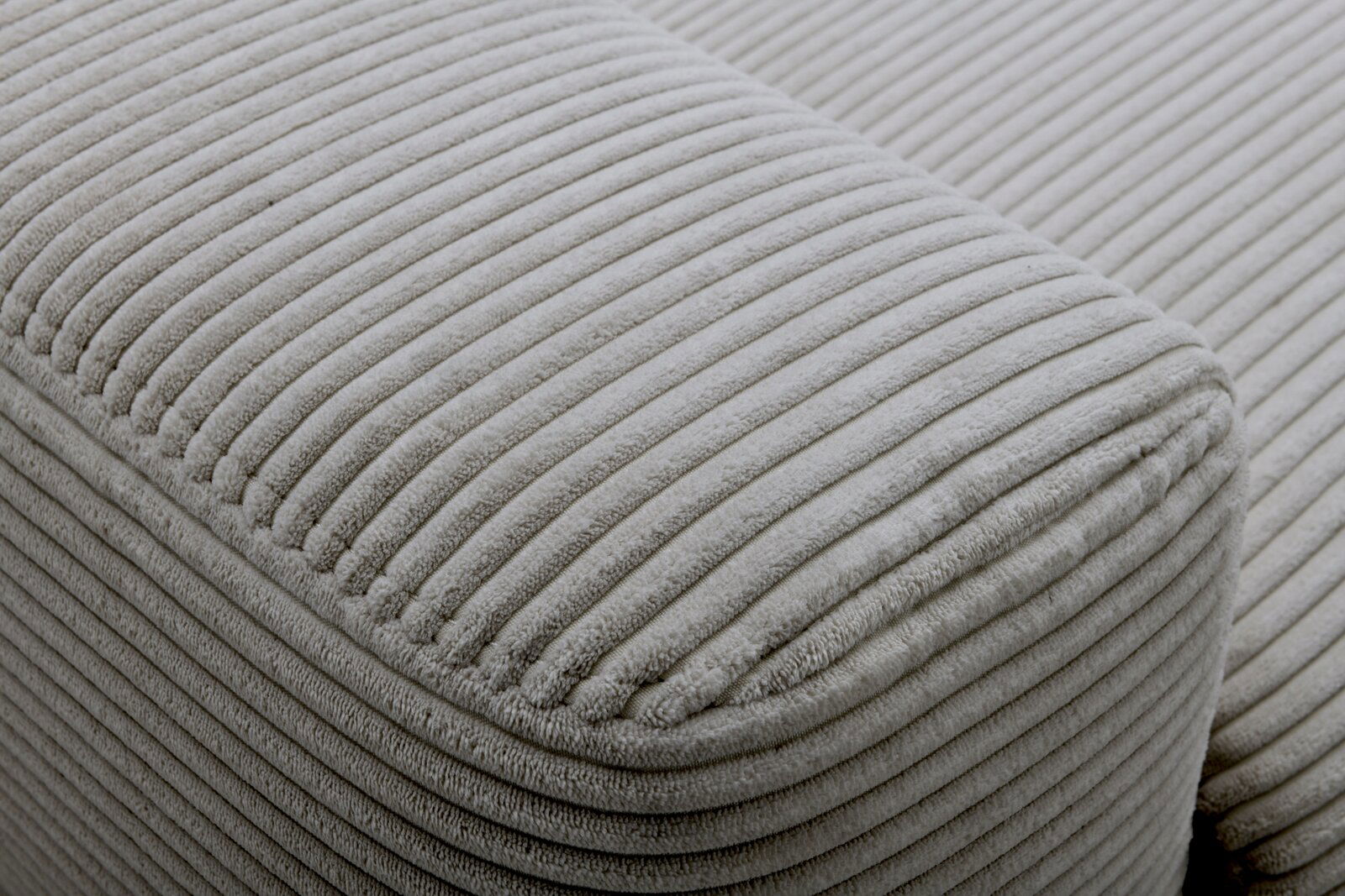 Nahaufnahme eines grauen, gerippten Stoffes eines Funktionssofas aus seitlicher Perspektive.