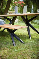 Holzbank mit schwarzem Metallgestell im Garten, seitliche Perspektive