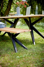 Holzbank mit schwarzem Metallgestell im Garten, seitliche Perspektive