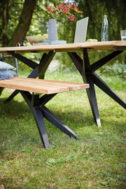 Holzbank mit schwarzem Metallgestell im Garten, seitliche Perspektive