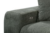 Nahaufnahme einer grünen Sofaecke mit strukturiertem Stoffbezug und einem silbernen Knopf an der Armlehne, seitliche Perspektive.