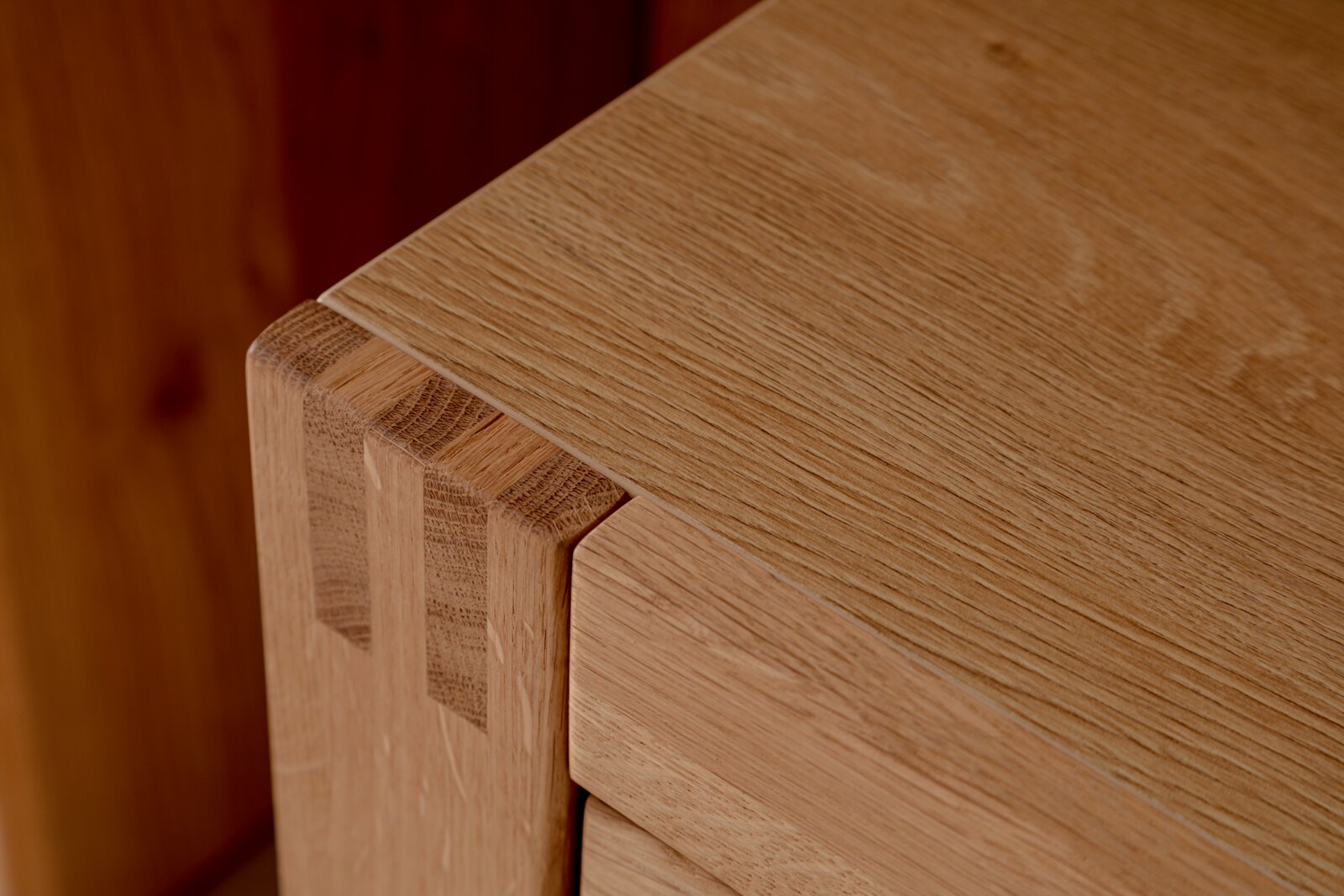 Detailansicht einer Ecke eines Highboards aus Holz mit sichtbarer Maserung und präziser Verarbeitung.