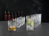 Ein Set von zwölf Kristallgläsern der Serie Highland, auf einer dunklen Oberfläche arrangiert. Im Vordergrund ein kurzes Glas mit Whisky und ein hohes Glas mit Gin Tonic und Limettenscheiben. Perspektive von vorne.