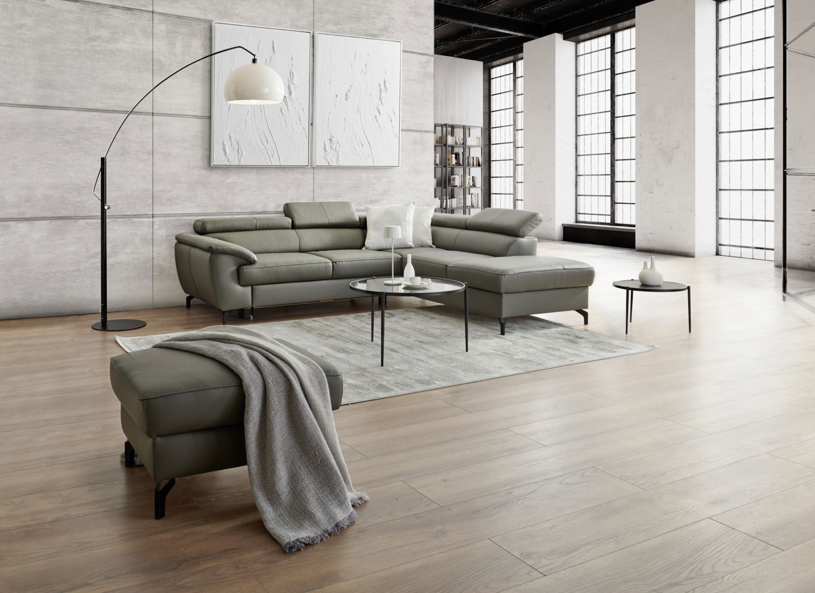 Moderne Eckgarnitur in einem stilvollen Wohnzimmer mit großen Fenstern, grauem Teppich und eleganten Beistelltischen, seitliche Perspektive.