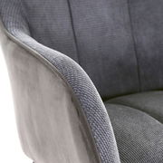 Nahaufnahme eines grauen Armlehnstuhls mit weicher Polsterung und texturierter Oberfläche, seitliche Perspektive