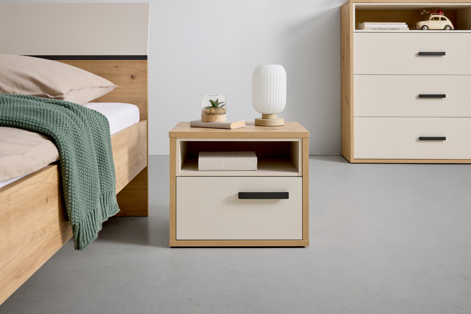 XORA Nachtkastje CASA MIA Houten nachtkastje met een lade en een open vak, met daarop een lamp en decoratie, gefotografeerd vanaf de voorkant.