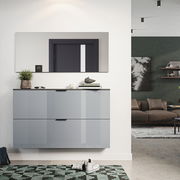 Moderner Schuhschrank in Hochglanzoptik, an der Wand montiert, mit zwei Schubladen, dekoriert mit Pflanzen und Büchern, in einem stilvollen Wohnzimmer mit Teppich und Sofa im Hintergrund. Perspektive: Frontalansicht.