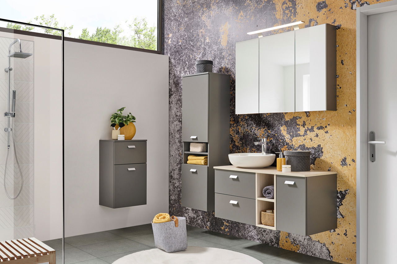 Moderner Badezimmer-Unterschrank in grauer Farbe, frontal betrachtet, mit Schubladen und offenen Fächern, dekoriert mit Handtüchern und Accessoires.