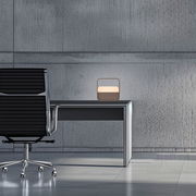 Moderne Tischleuchte PURE Go auf einem Schreibtisch in einem minimalistischen Büro, seitliche Perspektive.