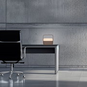 Moderne Tischleuchte PURE Go auf einem Schreibtisch in einem minimalistischen Büro, seitliche Perspektive.