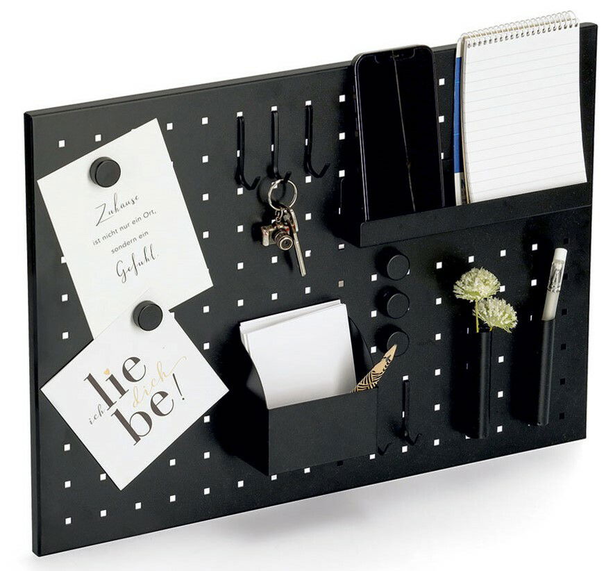 Schwarzes Memoboard mit Utensilien, darunter Haken für Schlüssel, Halterungen für Notizblöcke und Stifte, sowie dekorative Elemente. Perspektive: leicht von oben.